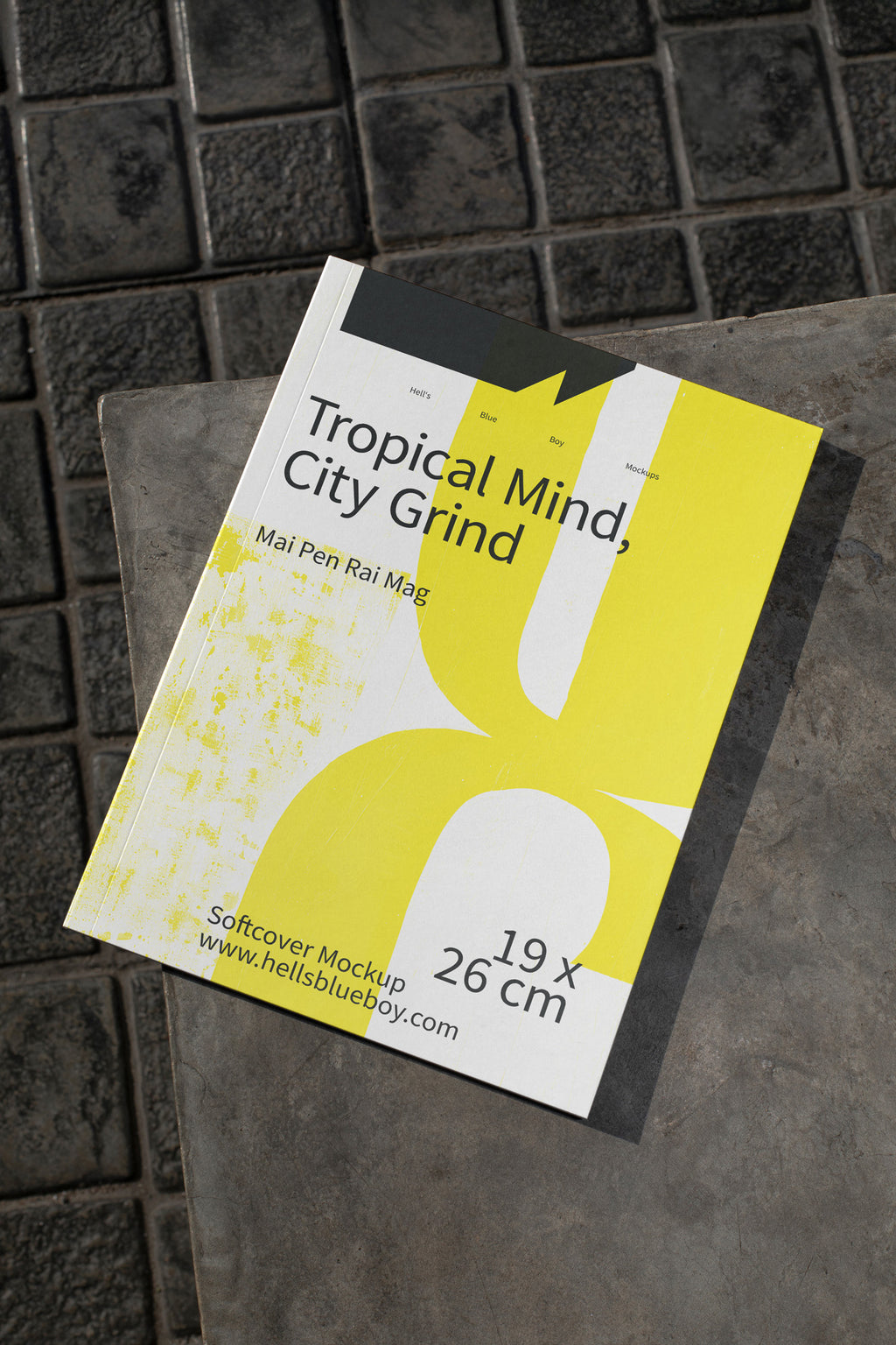 Softcover magazine mockup placed on dark brick tiles.