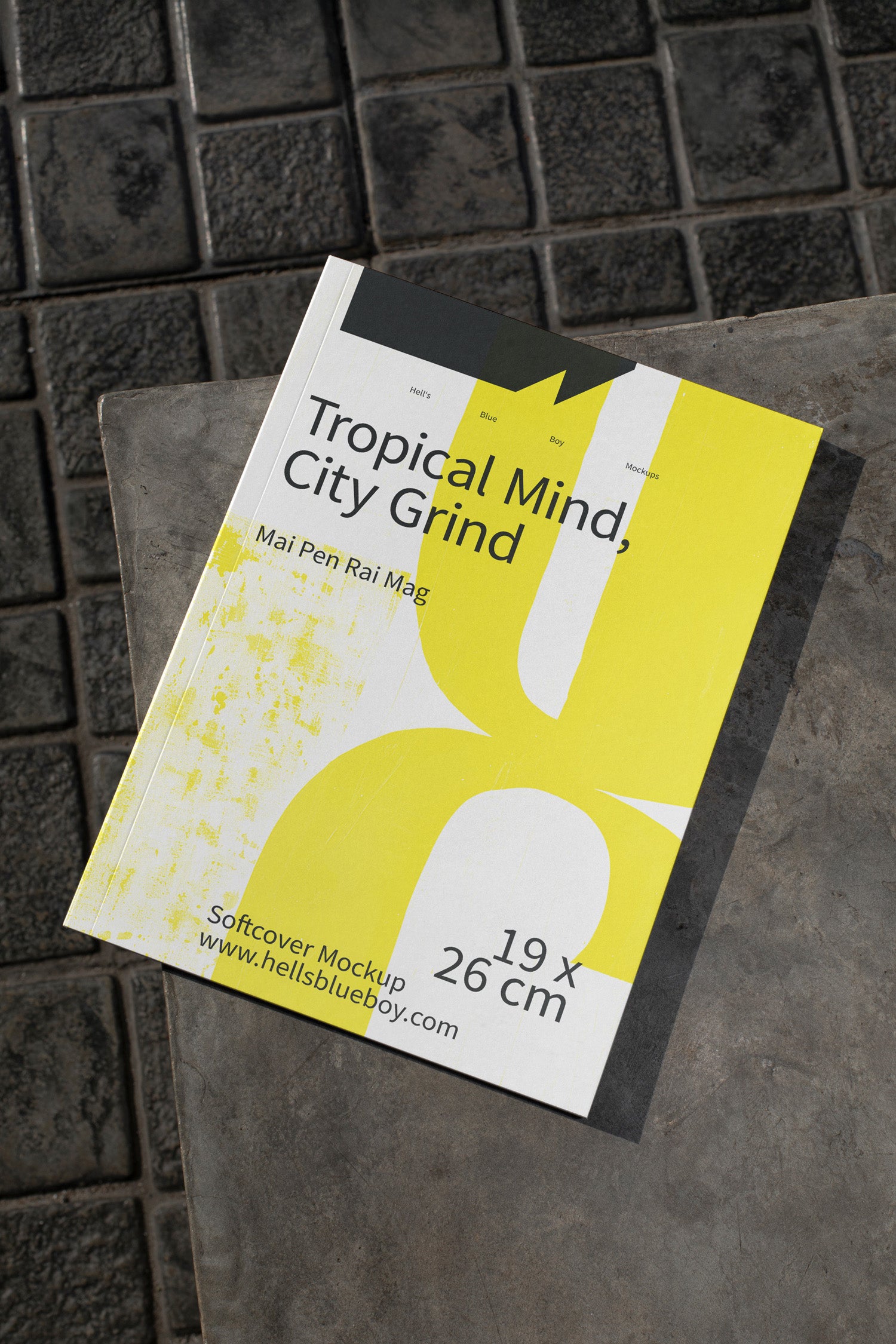 Softcover magazine mockup placed on dark brick tiles.